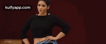 a woman in a black crop top is dancing in front of a red background .