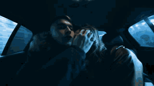 a man is holding a woman 's face in a dark car