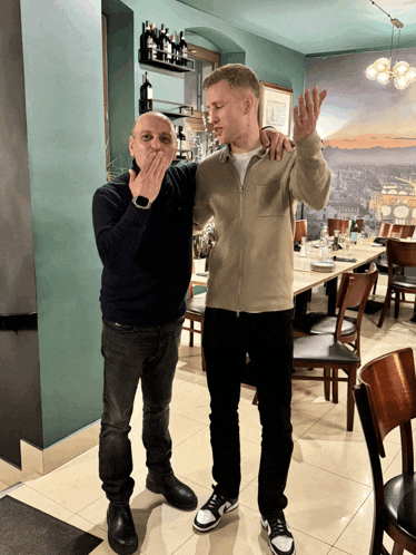 two men are standing in a restaurant with one covering his mouth