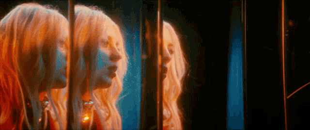 a woman is looking at herself in a mirror