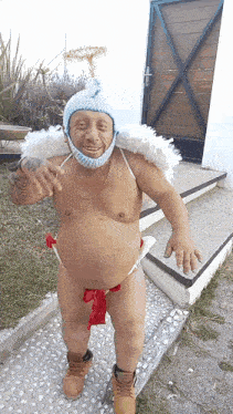 a naked man wearing a hat and wings is standing on a sidewalk