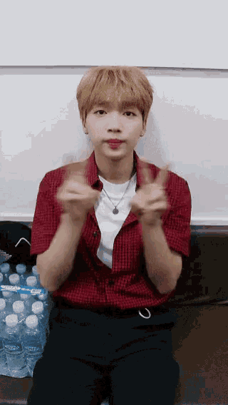 a young man in a red shirt is sitting on a couch with his hands together