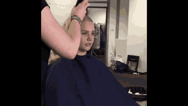 a woman in a blue cape is getting her hair cut by someone