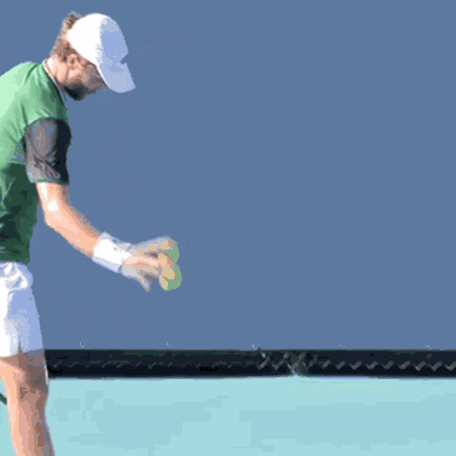 a man wearing a green shirt and a white hat looks up at the sky