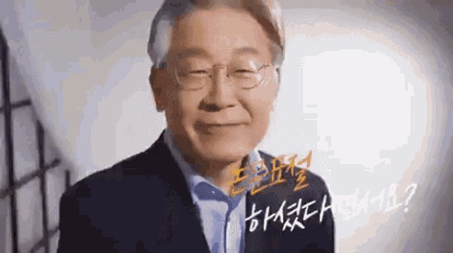 a man wearing glasses and a suit is smiling and talking .