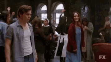 a group of people are dancing in a room with a man standing in the middle .