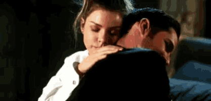 a man and a woman are hugging each other and the woman is touching the man 's face .