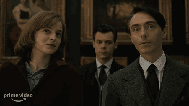 a woman and two men are standing next to each other in front of paintings and the word prime video is on the bottom right