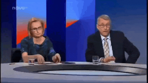a man and a woman are sitting at a table on a news show ..