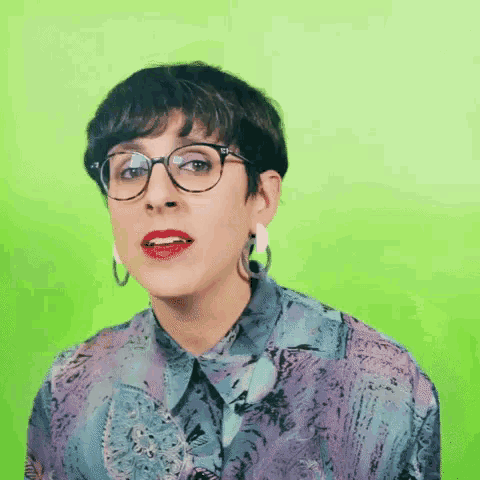 a woman wearing glasses and hoop earrings is making a face