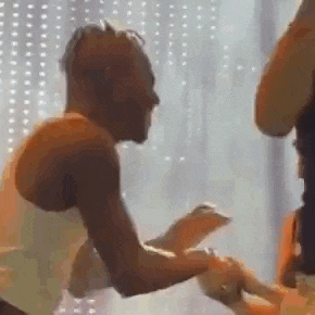 a man in a white tank top is dancing with a woman in a room .