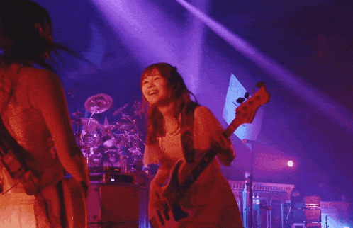 a woman in a white dress is playing a guitar in front of a microphone