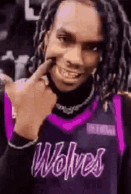 a man wearing a purple jersey with the word wolves on it is making a funny face .