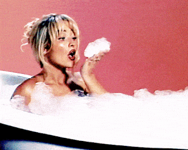 a woman is taking a bath in a bathtub while holding a piece of soap