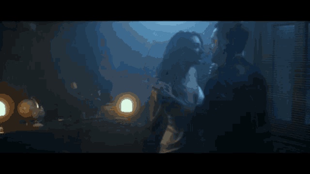 a man and woman are dancing in a dark room with a globe in the background