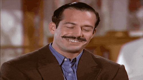 a man with a mustache is wearing a suit and smiling
