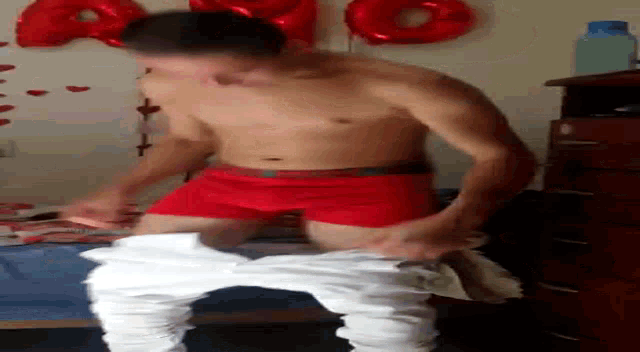 a shirtless man in red underwear is standing next to another man in white pants .