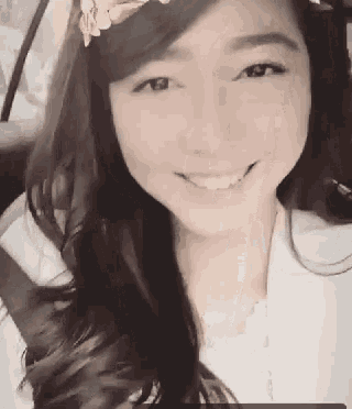 a woman is smiling while sitting in a car with a flower headband on her head .