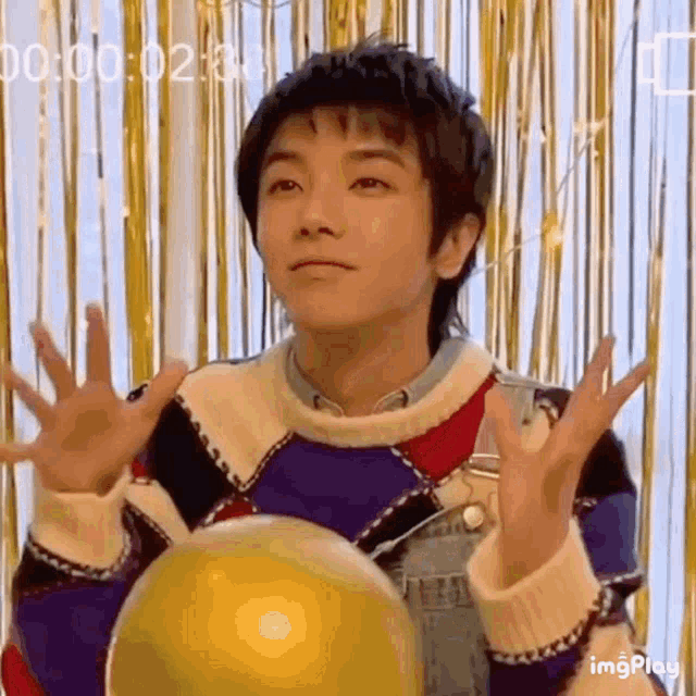 a young man is holding a yellow ball in his hands .