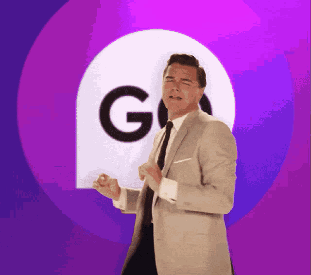 a man in a suit and tie is dancing in front of a large g