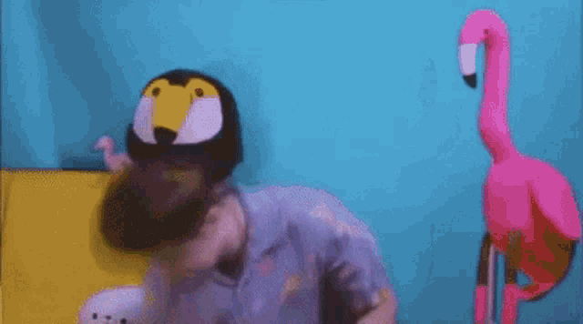 a man is singing into a microphone next to a stuffed flamingo and penguin .