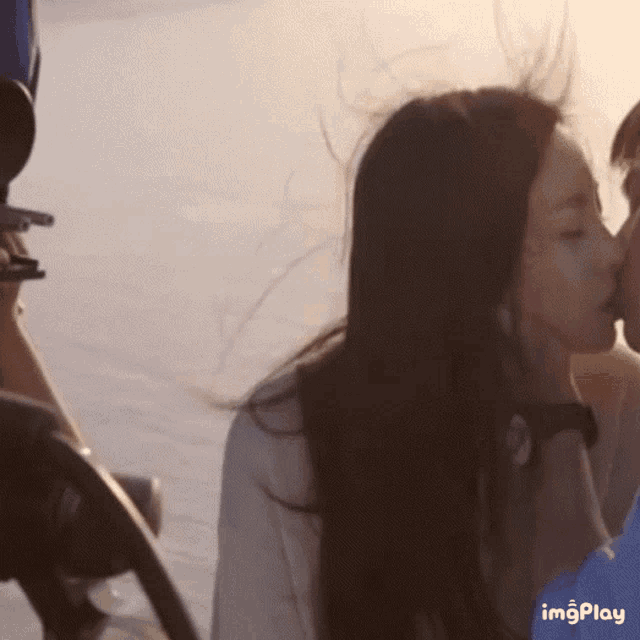 a woman is kissing a man on the cheek with a blue icon that says imgplay in the corner