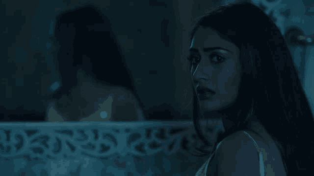a woman looks at her reflection in the mirror