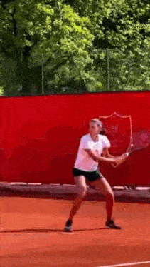 a woman is swinging a tennis racquet on a court .