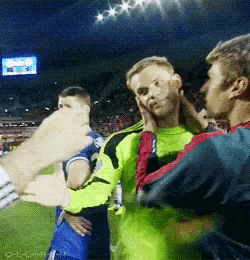 a group of soccer players are standing on a field and one of them is touching another 's face