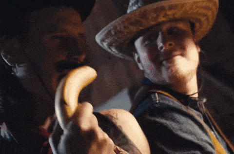 a man in a cowboy hat is holding a banana in his mouth
