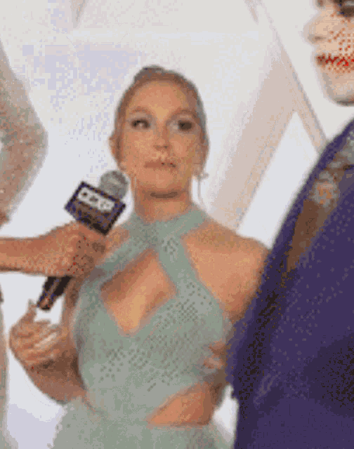 a woman in a green dress is being interviewed by a man in a purple suit while holding a microphone .