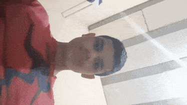 a young boy wearing a red shirt is taking a selfie