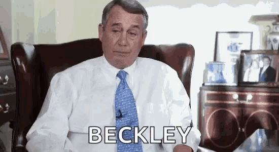 a man in a white shirt and blue tie is sitting in a chair and saying beckley