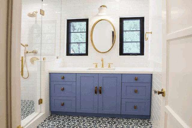 a bathroom with blue cabinets and black and white tile floors