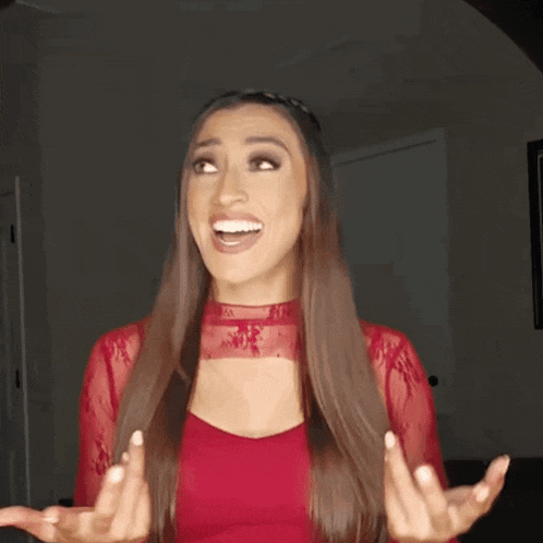 a woman with long hair is wearing a red dress and making a funny face .