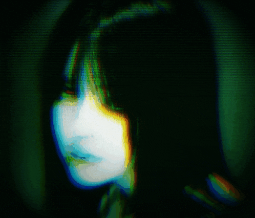 a blurry picture of a woman 's face with a green and blue glow