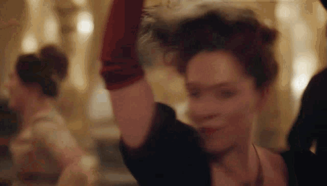 a woman wearing a red glove is dancing in a room with other women .