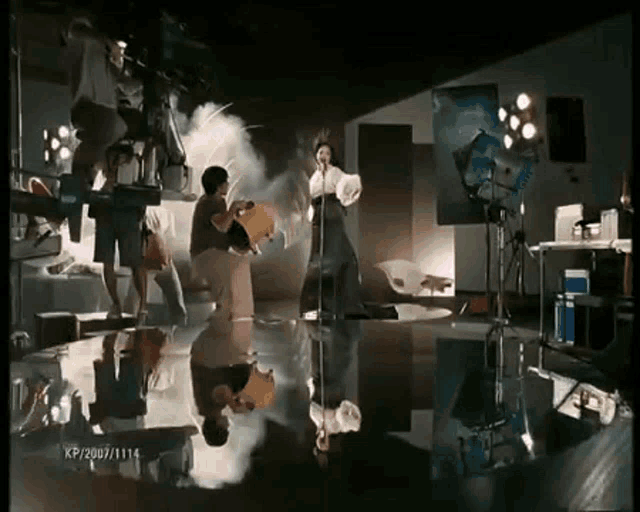 a woman singing into a microphone in a room with kp2007/114 written on the bottom right