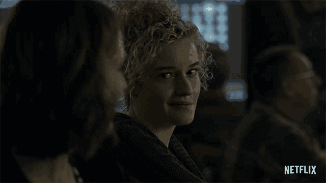 a woman with curly hair is sitting next to a man with a netflix logo in the corner