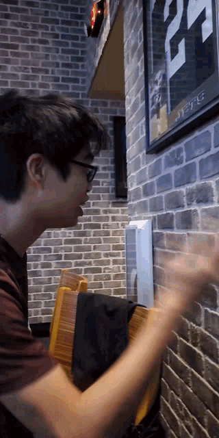 a man sitting in front of a brick wall with a poster on it that says 22