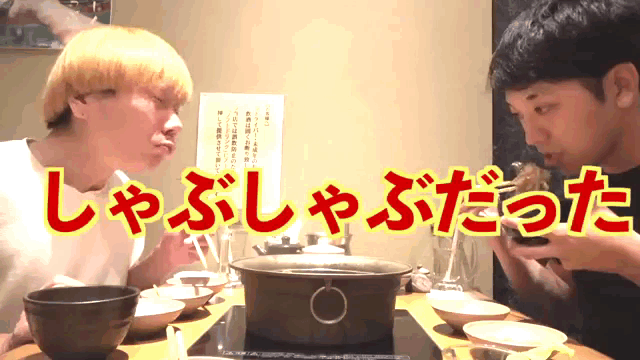 two men are sitting at a table with a sign that says ' l ' on it