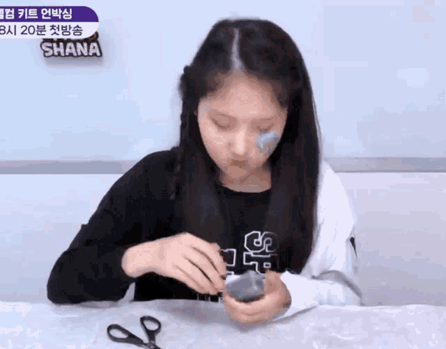 a girl sitting at a table with scissors and a sign that says shana on it