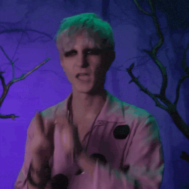 a man wearing a pink shirt with black polka dots is making a funny face