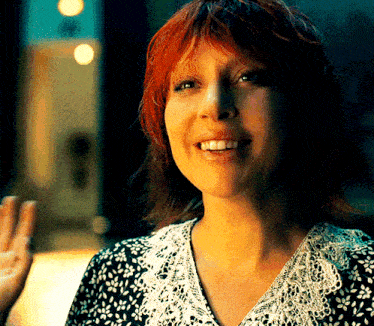 a woman with red hair wearing a black and white lace shirt