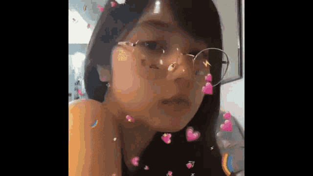 a close up of a girl wearing glasses with hearts coming out of her eyes .