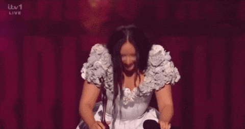 a woman in a white dress is holding a microphone and a knife .