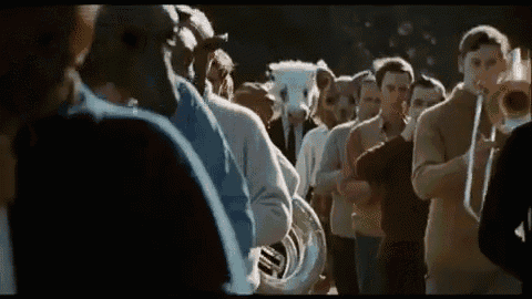 a group of people are standing in a line playing musical instruments .