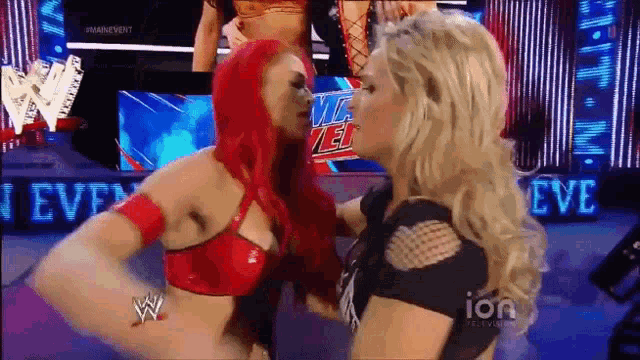 a woman with red hair is kissing another woman on a wrestling show