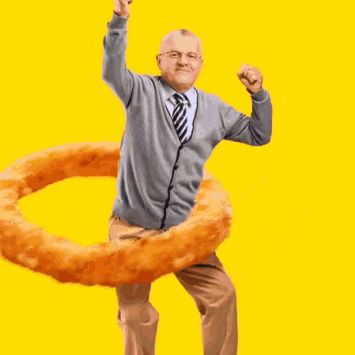 an elderly man is dancing with a large onion ring around his waist .