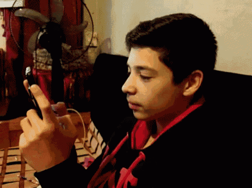 a young boy wearing headphones looks at his phone